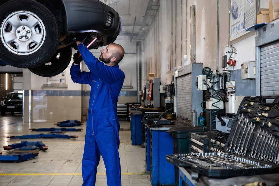 Mechanic working on the engine of a car that is on a hoist