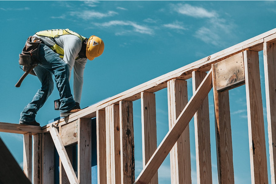 Carpenter standing on framing using a nail gun
